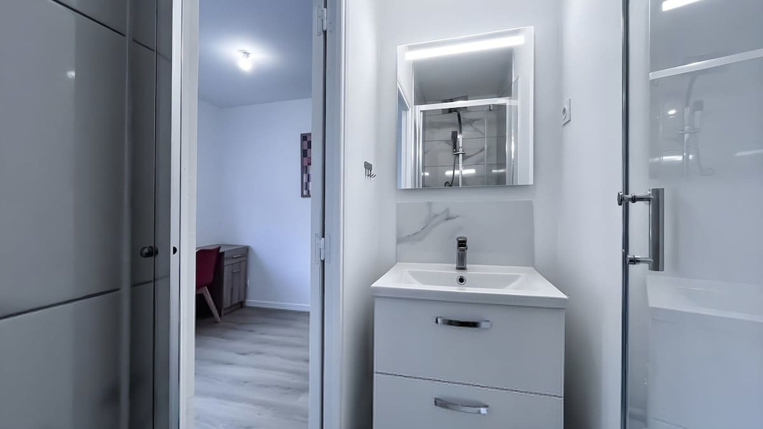 A modern bathroom with a white sink, a mirror above it, and a cabinet with drawers.