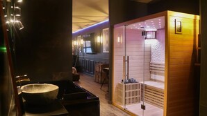 A modern interior with a stone basin, wooden sauna, and a well-lit corridor. - La Suite des Arcades Grand Place Sauna et Balneo (Arras)