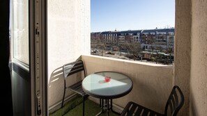 A balcony with a table and chairs, a view of buildings, and a clear sky. - Cosy Place d Armes au 3eme Etage (Douai)