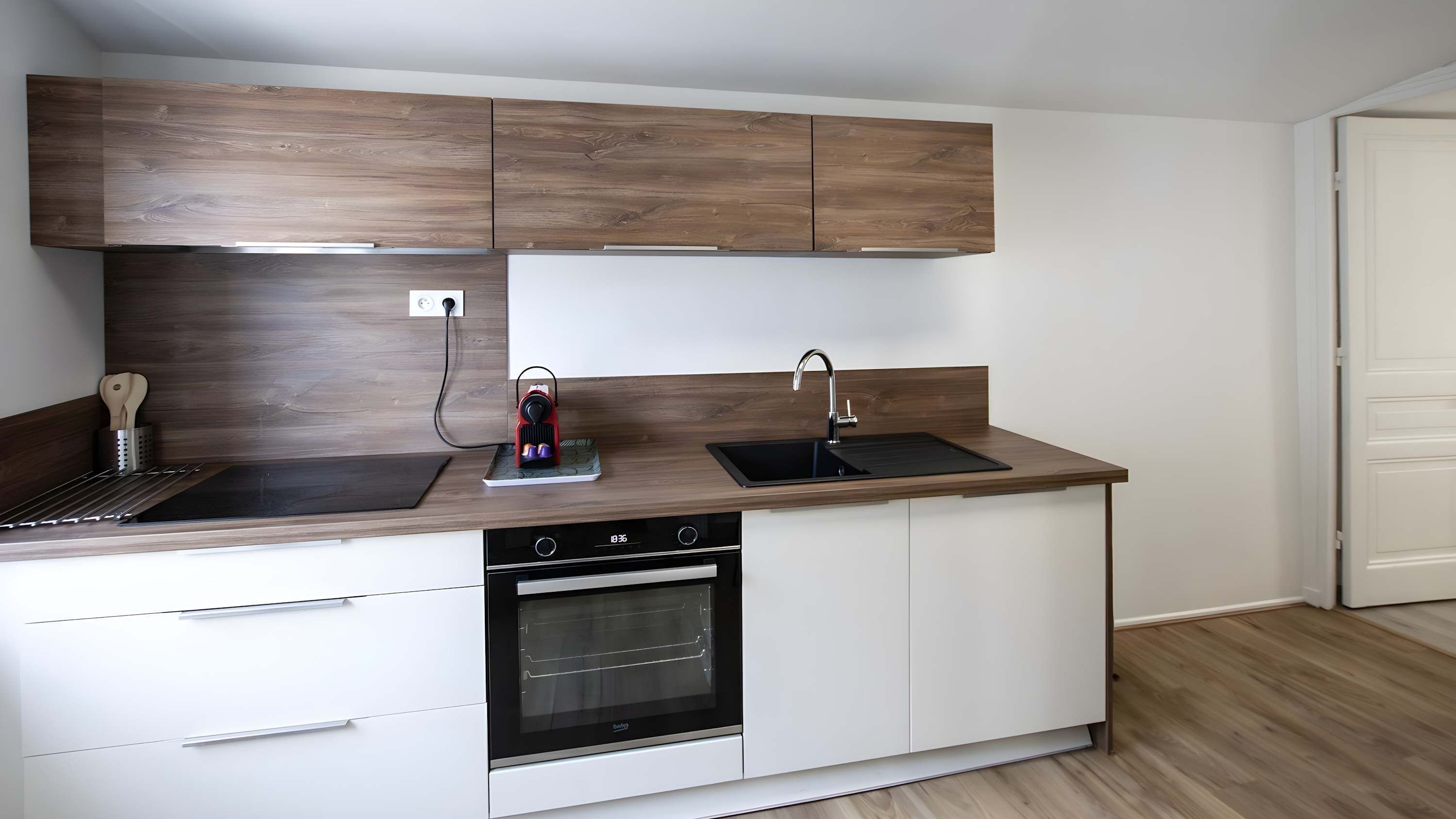 A compact kitchen with a dishwasher, oven, and a sink.