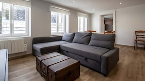 A modern living room with a grey sectional sofa, a wooden chest of drawers, and a radiator. - Le Perchoir de Maurice Calme et Cosy (Arras)