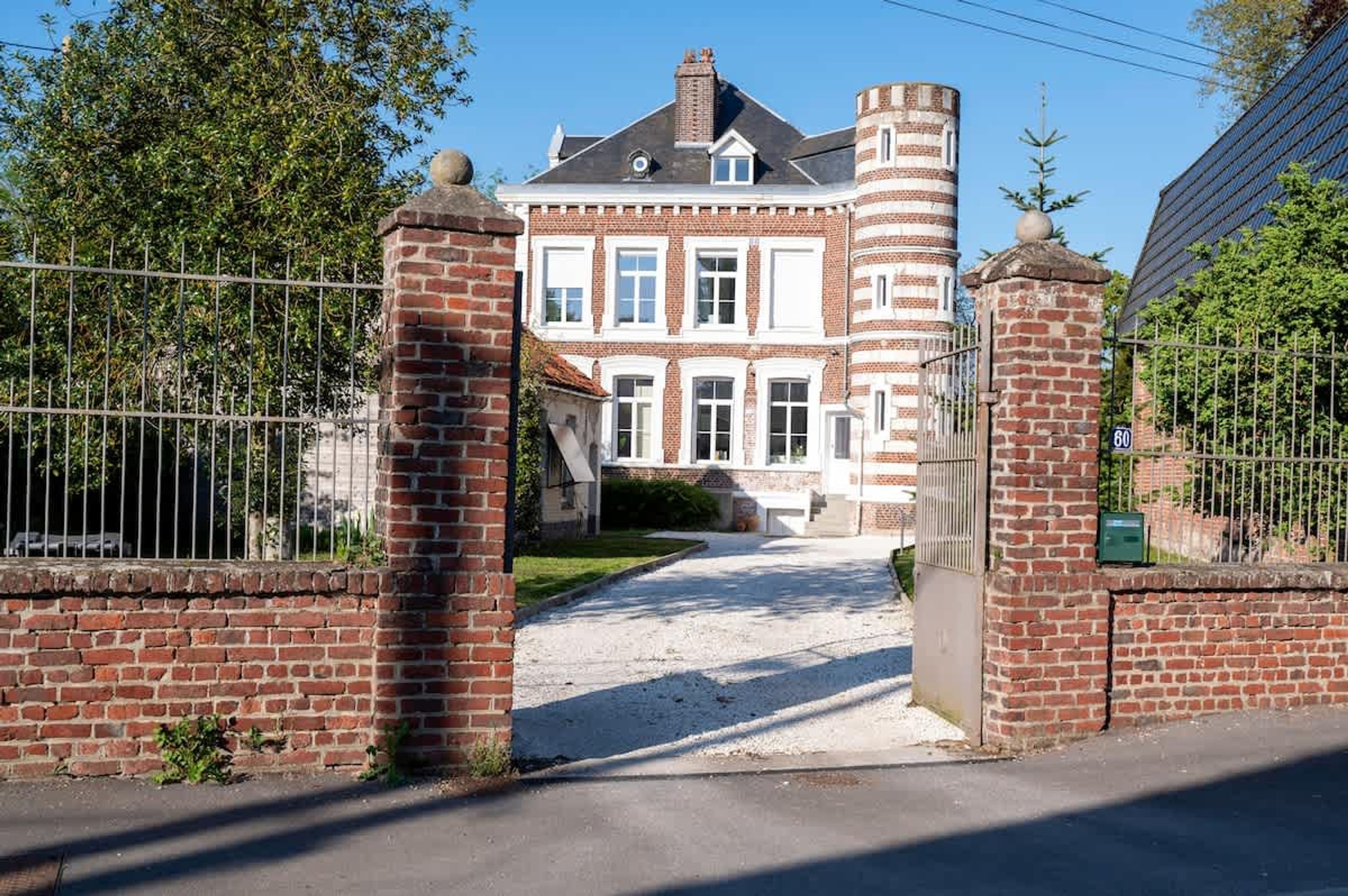 A large, historic building with a gated entrance, a brick facade, and a prominent tower.