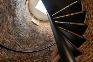 A spiral staircase with a skylight, brick walls, and a wooden platform at the top. - The Helios Duplex Comfort Elegance (Aire-sur-la-Lys)