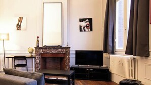 Una sala de estar con chimenea, sofá, televisor y radiador.