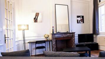 A living room with a sofa, a TV, a fireplace, and a large mirror.