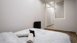 Un dormitori amb un llit, una cadira i una porta corredissa que dona a un bany.