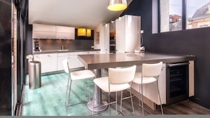 Uma cozinha moderna com ilha central, banquetas e luminária pendente.