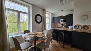Una cocina moderna con una isla central, una zona de comedor con una mesa redonda y un ventanal con vistas a árboles.
