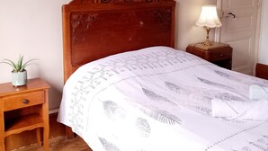 A bedroom with a wooden bed, a bedside table with a lamp, a small plant, and a framed picture on the wall. - Le G te des Pr s Terrasse Parking Gratuit 5pers (Lievin)