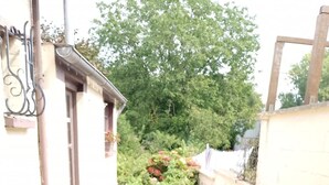 A patio with a table and chairs, surrounded by a brick wall and greenery. - Le G te des Pr s Terrasse Parking Gratuit 5pers (Lievin)