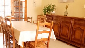 A dining area with a wooden table and chairs, a cabinet, and a potted plant. - Le G te des Pr s Terrasse Parking Gratuit 5pers (Lievin)