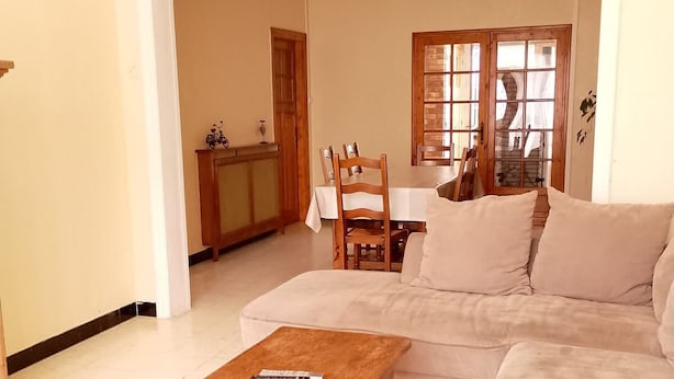 A living room with a sofa, a wooden coffee table, and a dining area with a table and chairs. - Le G te des Pr s Terrasse Parking Gratuit 5pers (Lievin)