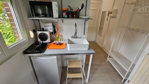 Pieni, käytännöllinen keittiö, jossa on mikroaaltouuni, pesuallas ja pieni jääkaappi.