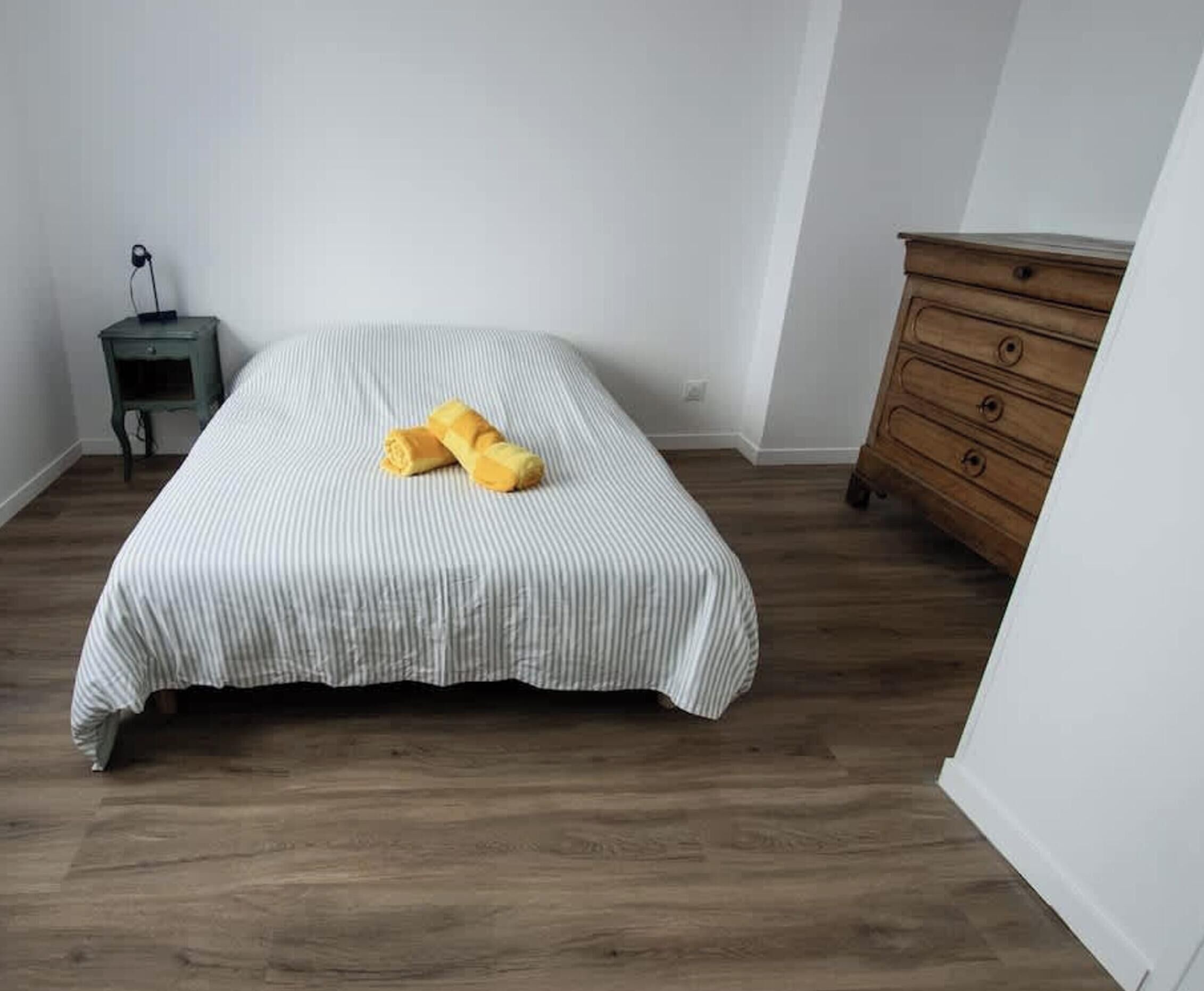 Une chambre avec un lit, une commode en bois et une table de chevet.