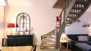 A modern living room with a dining area, a staircase, and a view of the outside. - Petit Calais Tourcoing Maison Culture et art (Tourcoing)