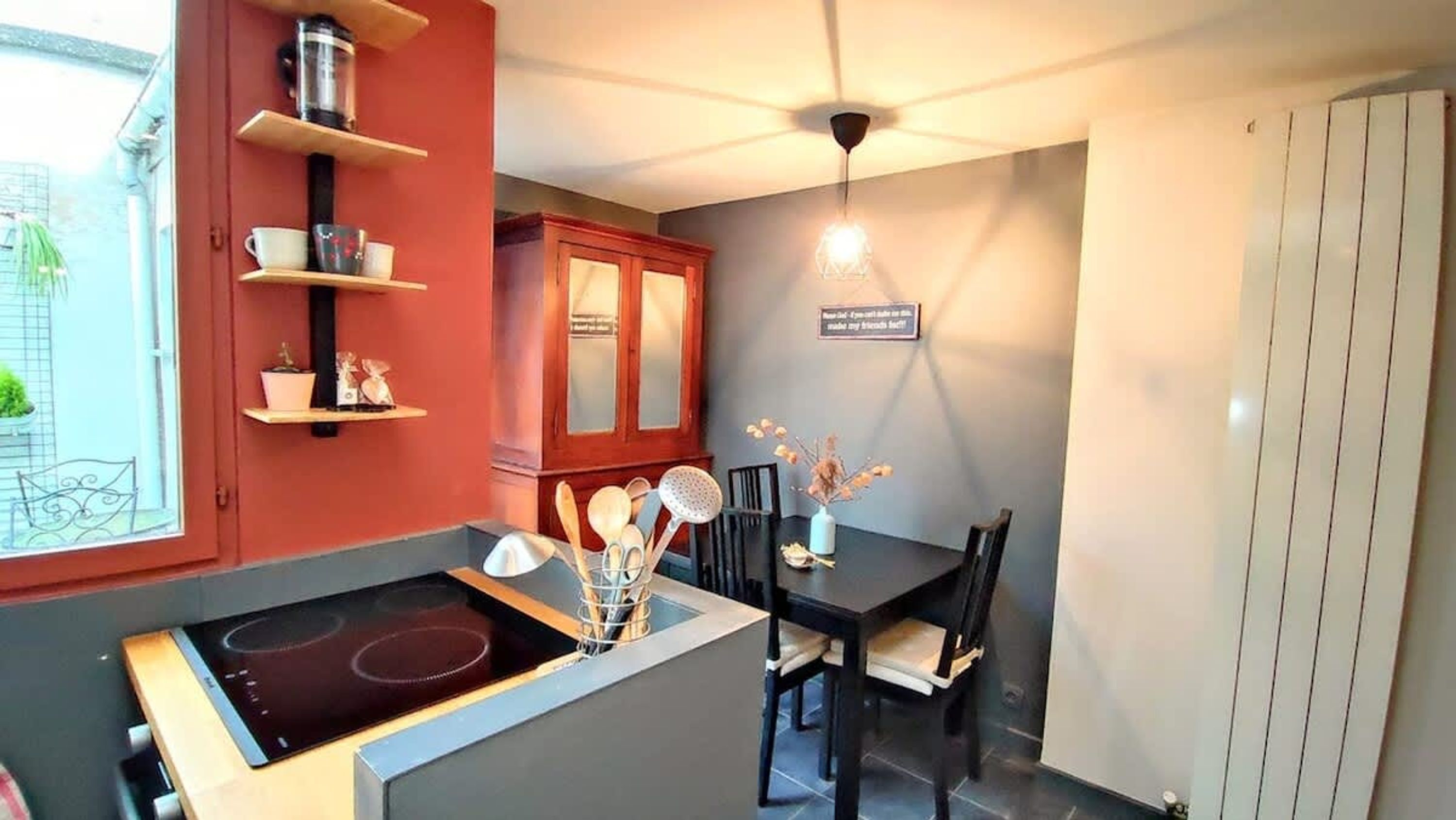 A compact kitchen with a built-in stove, wooden cabinets, and a dining area with a table and chairs.