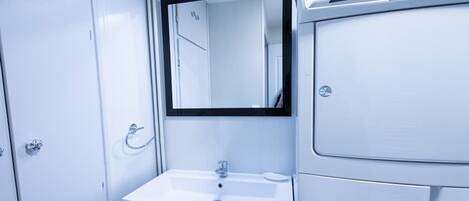 A small, white bathroom with a sink, mirror, and a door.