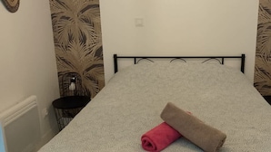 A narrow room with a single bed, a small table, and a chair. - Chez Serge N 107 Jardin Parking Animaux 4 Pers (Noeux-les-Mines)