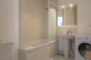 A bathroom with a bathtub, a sink, a mirror, and a washing machine. - Vue sur le Clocher in Lens (Lens)