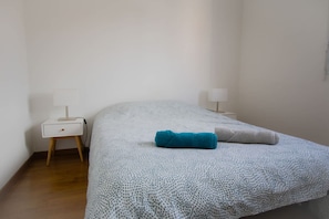 A bedroom with a bed, a nightstand, a lamp, and a wall-mounted light. - Vue sur le Clocher in Lens (Lens)