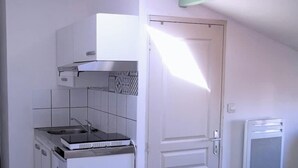 Une cuisine de taille réduite, équipée d’une cuisinière, d’un évier et d’un petit réfrigérateur.