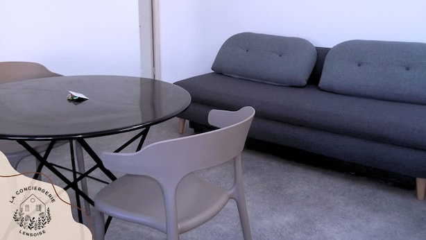 Une pièce avec une table ronde, un canapé gris et une chaise blanche.