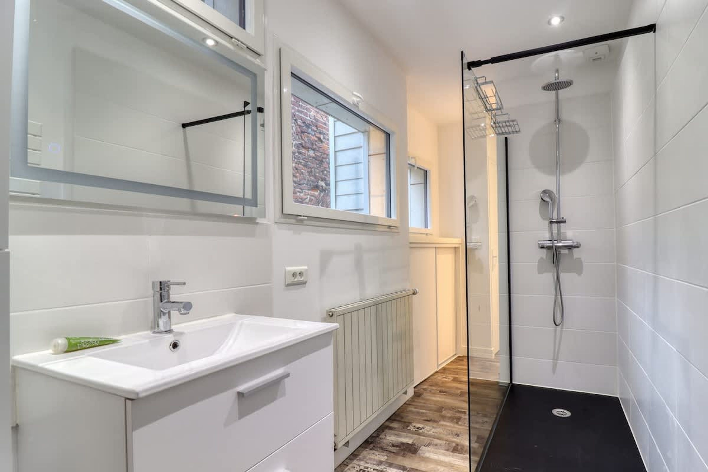 Ein modernes Badezimmer mit Waschbecken, Spiegel und Dusche.