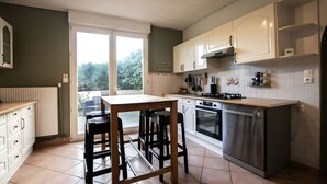 Uma cozinha com mesa e cadeiras, fogão, forno e armários brancos.