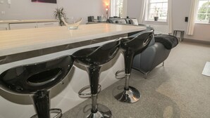 Una cocina moderna con barra, taburetes, una mesa de comedor y un cuadro en la pared.