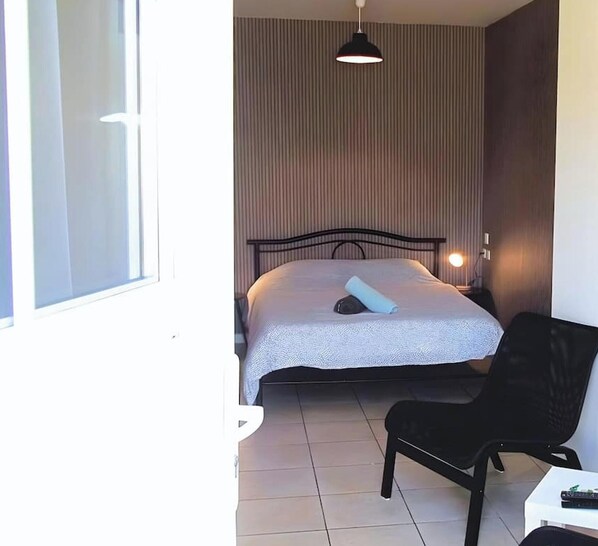 A room with a bed, a chair, a desk, a lamp, and a window. - Chez Serge N 102 Wifi Parking Gratuit 2pers (Noeux-les-Mines)