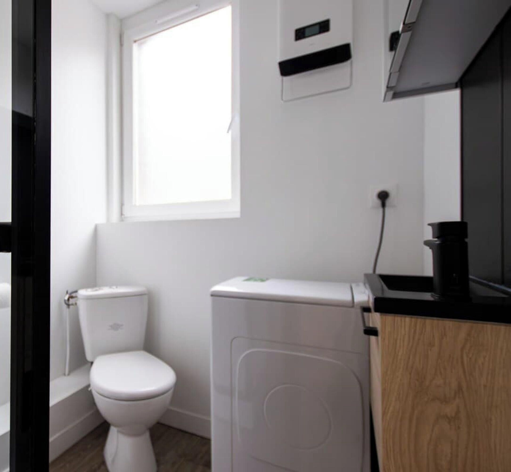 A modern bathroom with a toilet, bidet, and a sink with a black countertop.