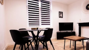 Un salon moderne comprenant un coin repas, un téléviseur à écran plat et une cheminée.
