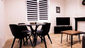 A modern living room with a dining area, a flat-screen TV, and a fireplace.