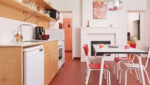 A modern kitchen with white appliances, a dining table with chairs, and a fireplace. - Chez Marie Jeanne -La Cite des Electriciens- 2pers (Bruay-la-Buissiere)