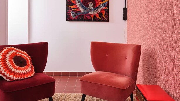 A room with two red armchairs, a wooden table, a colorful painting on the wall, and a patterned wall. - Chez Marie Jeanne -La Cite des Electriciens- 2pers (Bruay-la-Buissiere)