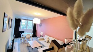 A living room with a sofa, coffee table, and a dining area with chairs. - Atelier Wagram Au Coeur de Troucoing (Tourcoing)