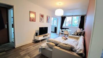 A modern living room with a sofa, TV, and artwork on the wall.