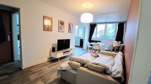 A modern living room with a sofa, TV, and artwork on the wall. - Atelier Wagram Au Coeur de Troucoing (Tourcoing)
