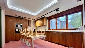 A modern kitchen with wooden cabinets, a dining table with chairs, and a large window. - Maison 5 Chambres et Parking Gratuit (Arras)