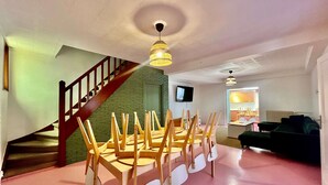 A room with a staircase, a dining table with chairs, a television, and a sofa. - Maison 5 Chambres et Parking Gratuit (Arras)