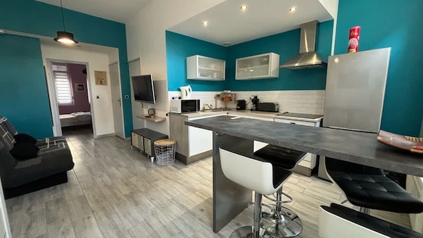 A modern kitchen with a central island, white cabinets, and a stainless steel range hood.