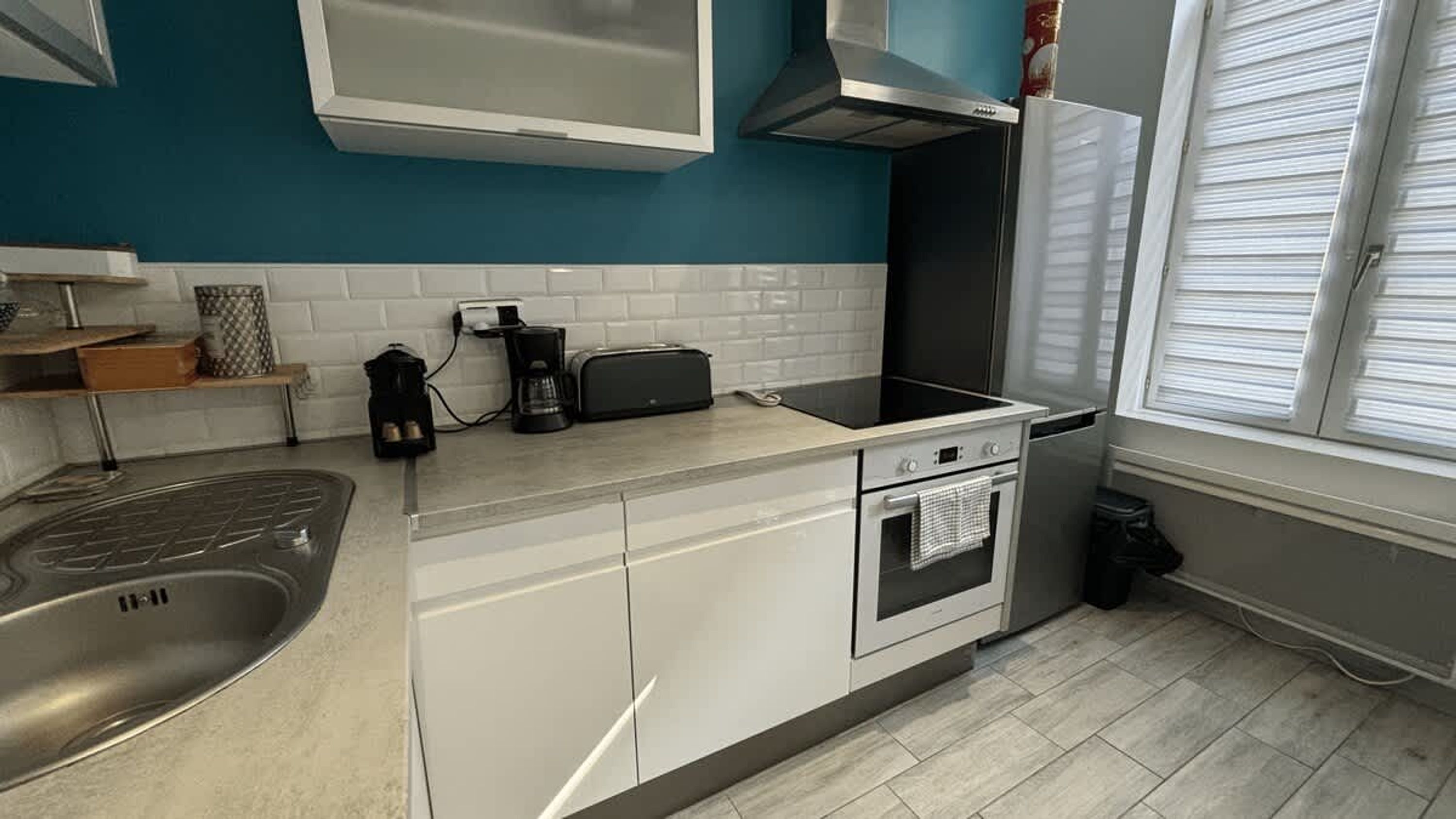 Una cocina moderna con un fregadero, estufa y horno, una cafetera y un tostador sobre la encimera.