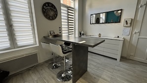 A modern kitchen with a central island, bar stools, a wall clock, and a large mirror.