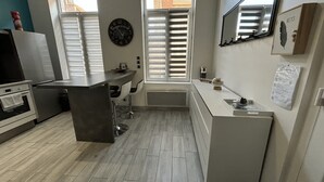 A modern kitchen with a central island, white cabinetry, and a window with shutters.