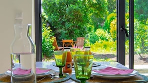 A dining table set with plates, napkins, and glasses, with a bottle of water and a glass of juice. - Le Matisse - Centre - Jardin au Calme - Lumineux (Béthune)