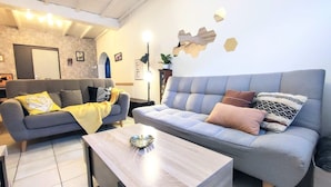 Uma sala de estar moderna com dois sofás, uma mesa de centro e um objeto decorativo na parede.