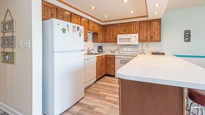 Una cocina con armarios de madera, un refrigerador blanco, un microondas y una estufa.