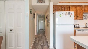 Un pasillo con un refrigerador blanco, armarios de madera y un reloj en la pared.