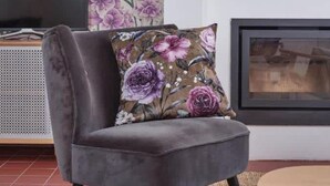 A grey armchair with a floral cushion, a television, and a fireplace in a living room. - Chez Alice Sauna 4pers - La Cite des Electriciens (Bruay-la-Buissiere)