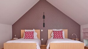 A bedroom with two beds, a sloped ceiling, and a patterned wall. - Chez Alice Sauna 4pers - La Cite des Electriciens (Bruay-la-Buissiere)